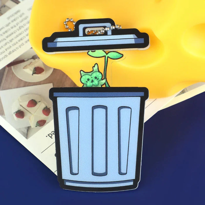 Custom acrylic magnet charm shaped like a trash bin with a green cat plant design
