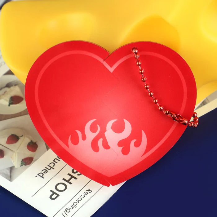Red acrylic heart-shaped charm with flame design and metal keychain on magazine background