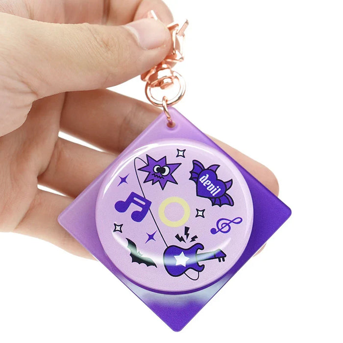 Hand holding custom acrylic double rotating keychain with purple music and bat designs