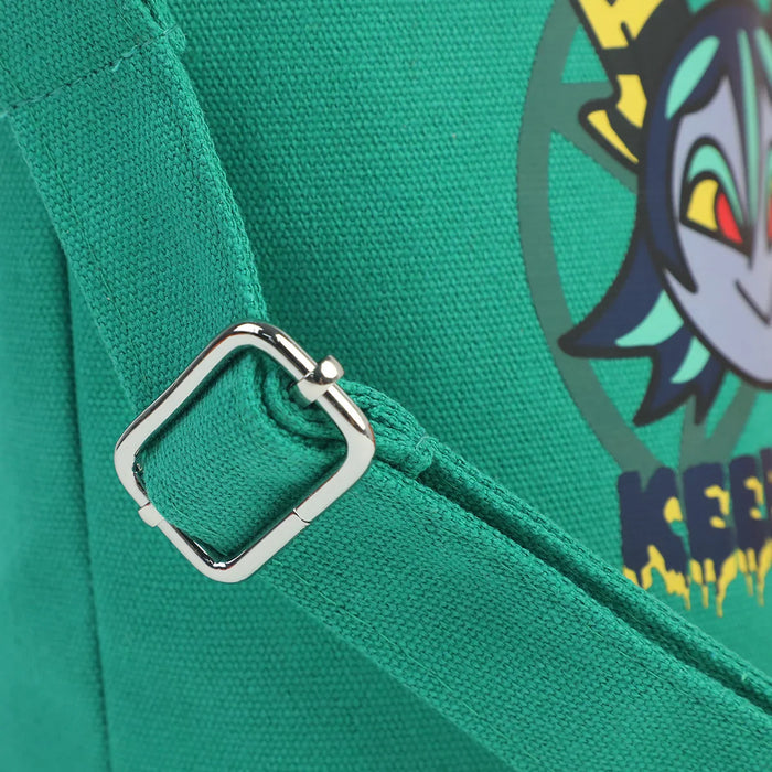 Close-up of green canvas bucket bag strap with silver buckle and colorful cartoon graphic.