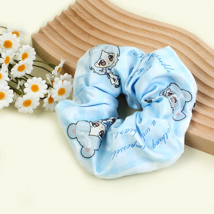 Custom light blue anime hair tie scrunchie with chibi character print, daisies, and wood prop