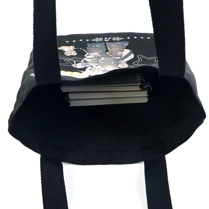 Black custom canvas tote bag with illustrated design, holding spiral notebooks inside.