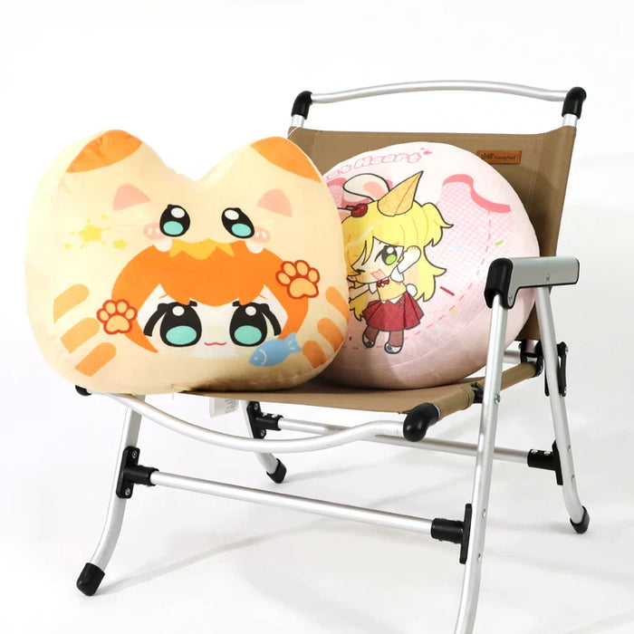 Two plush anime throw pillows with colorful cartoon designs on a folding chair.