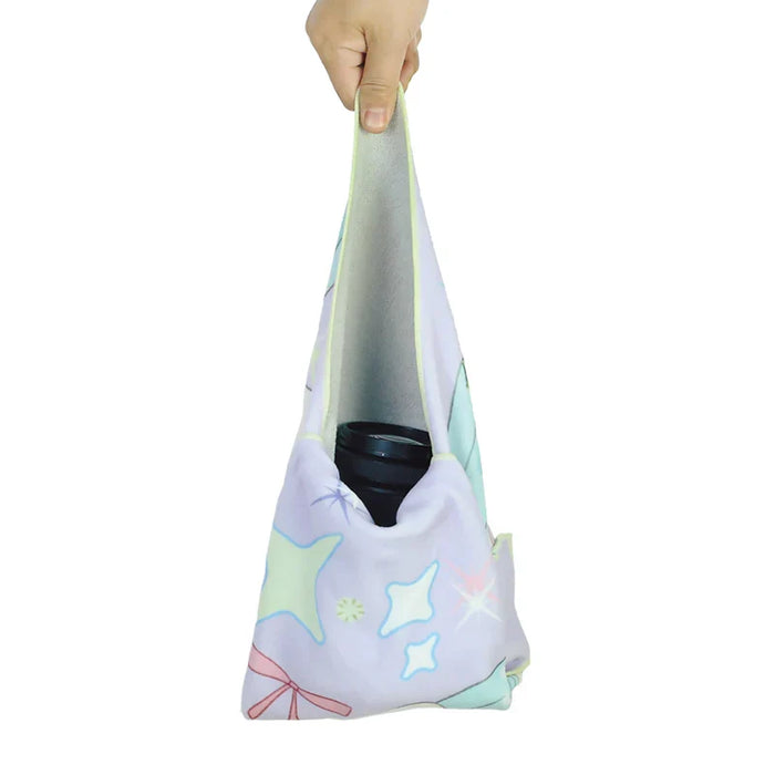 Hand holding pastel star-patterned reusable cloth wrap carrying a camera lens
