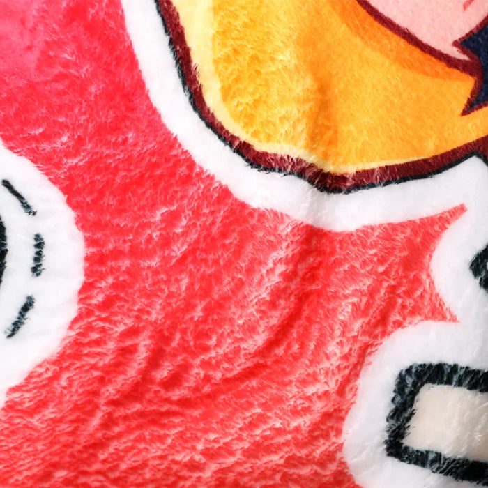 Close-up of soft coral fleece blanket with colorful cartoon print, plush texture visible