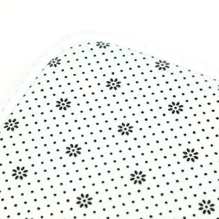 Close-up of a non-slip coral fleece floor mat with black dotted floral pattern