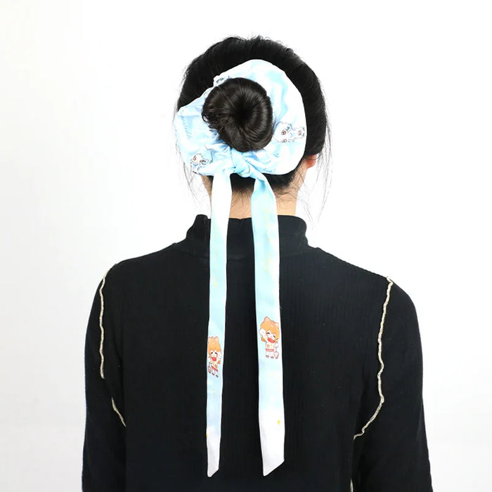 Woman with hair bun tied by a custom blue silk scarf featuring cute cartoon characters