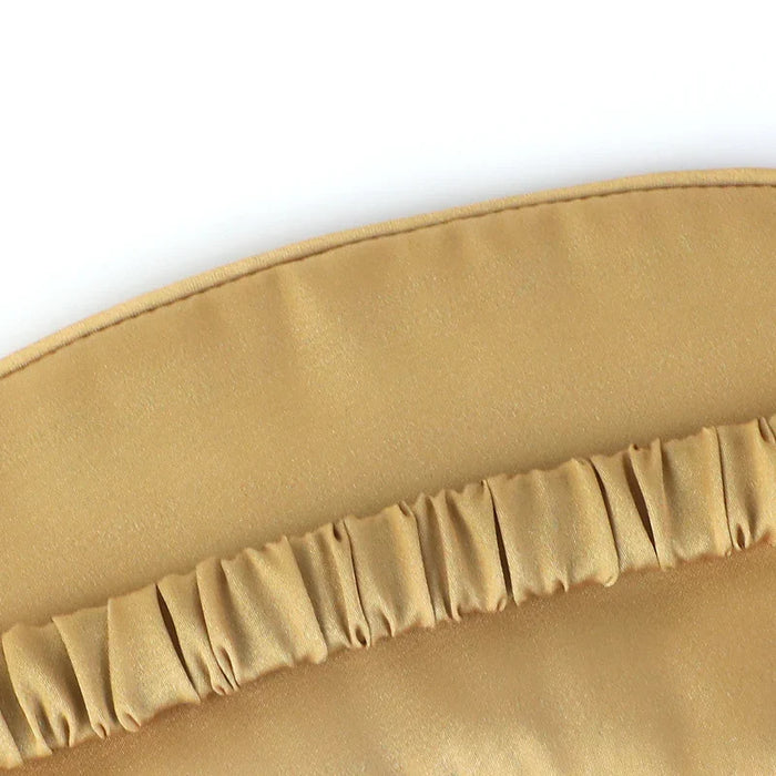 Close-up of a gold silk-like sleep mask with ruched elastic strap, luxury eye mask
