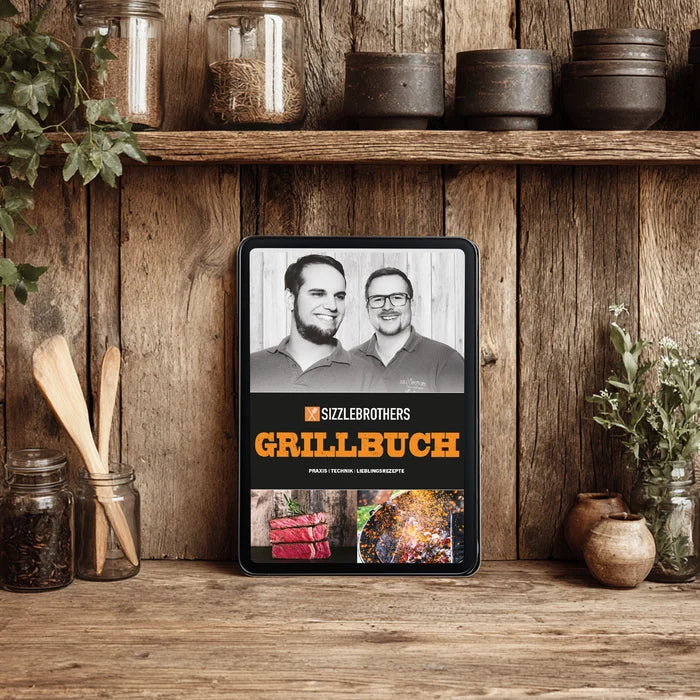 Ein Tablet mit einem Grillbuch vor einem Holzregal mit Küchenutensilien.