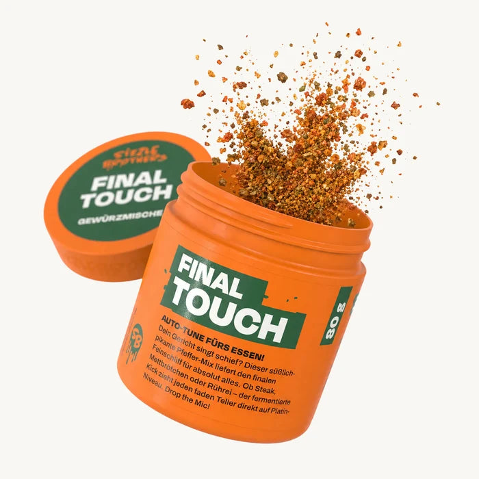 Oranger Behälter mit Text "FINAL TOUCH", Gewürzpulver spritzt heraus.