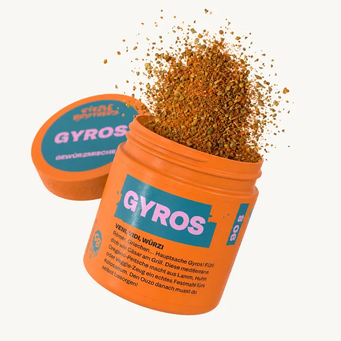 Orangene Dose mit Aufschrift 'GYROS', rotbraune Gewürze flocken heraus.