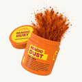 Oranger Behälter mit Text "MAGIC DUST", Gewürzpulver spritzt heraus.
