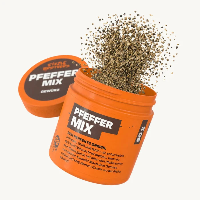 Orangene Dose mit Aufschrift 'PFEFFER MIX', Gewürz flockt heraus.